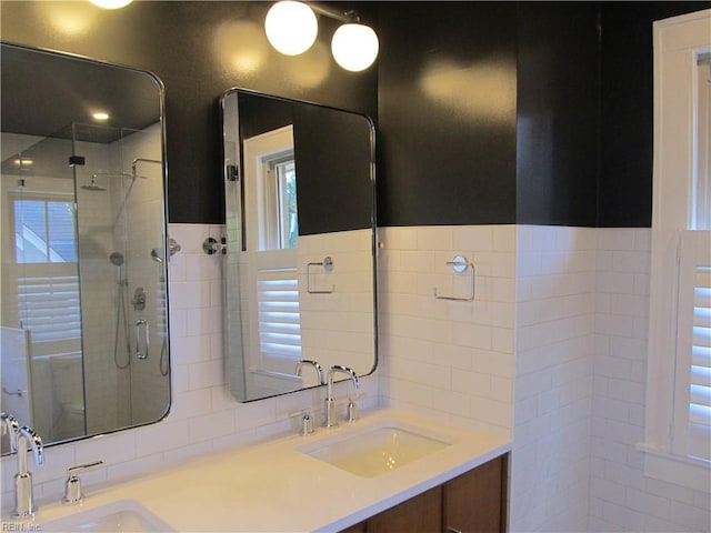 bathroom with vanity, tile walls, and a shower with shower door