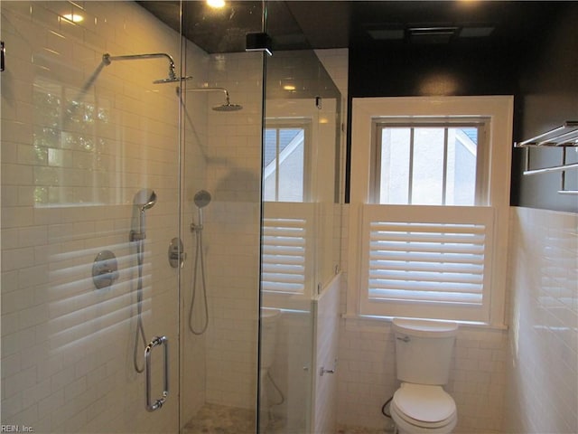 bathroom with tile walls, toilet, and an enclosed shower