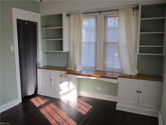 unfurnished office featuring built in desk and dark hardwood / wood-style flooring