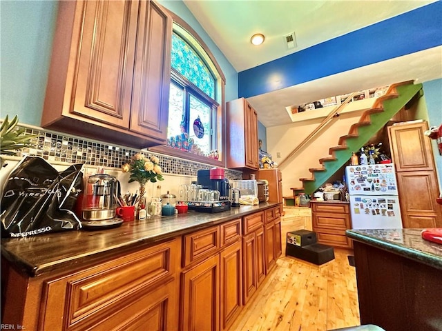 1057 W Rd, Chesapeake, VA 23323 - kitchen featuring freestanding refrigerator, brown cabinetry, decorative backsplash, light wood finished floors, and lofted ceiling