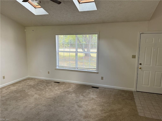 unfurnished room featuring a textured ceiling, ceiling fan, carpet floors, and a skylight