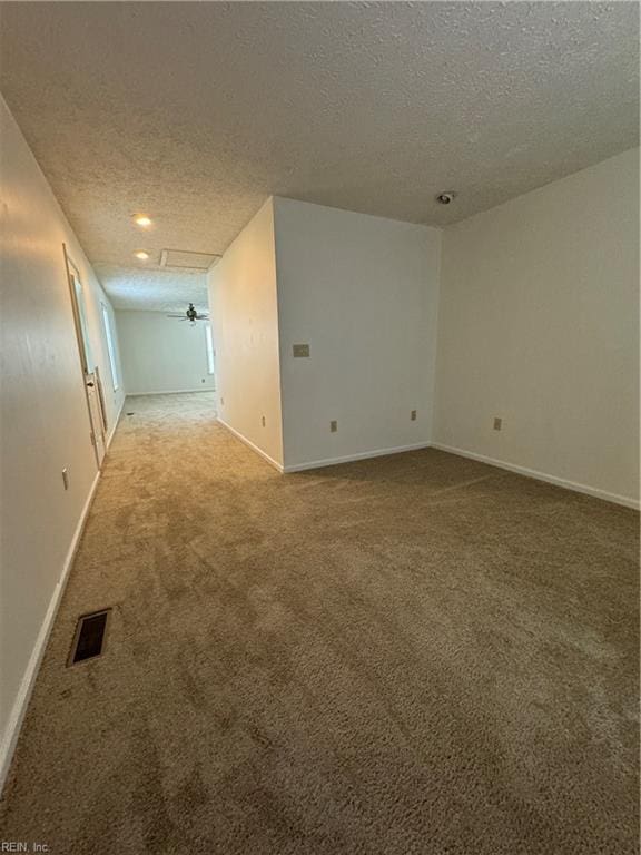 empty room with ceiling fan, a textured ceiling, and light colored carpet