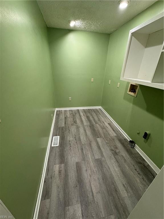 clothes washing area with a textured ceiling, hardwood / wood-style flooring, and washer hookup