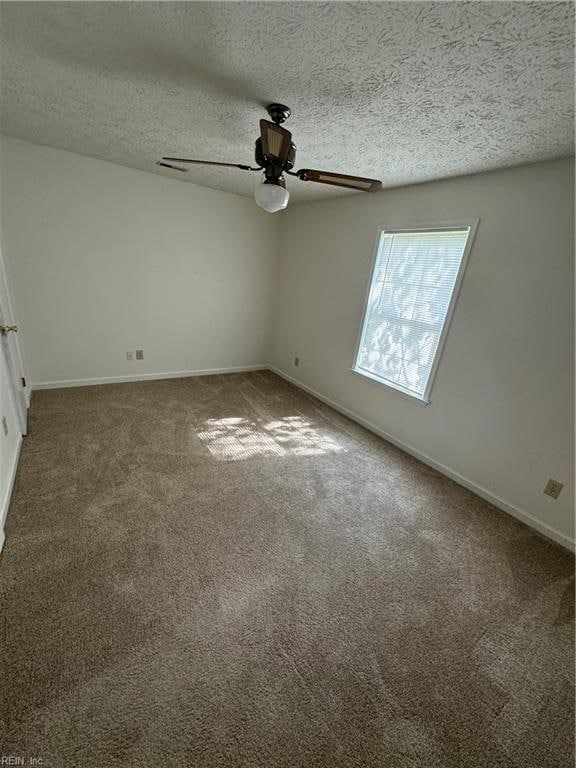 unfurnished room with ceiling fan, a textured ceiling, and dark colored carpet