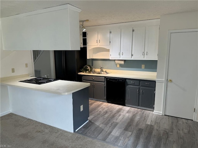 kitchen with black appliances, light wood-type flooring, a textured ceiling, kitchen peninsula, and white cabinetry