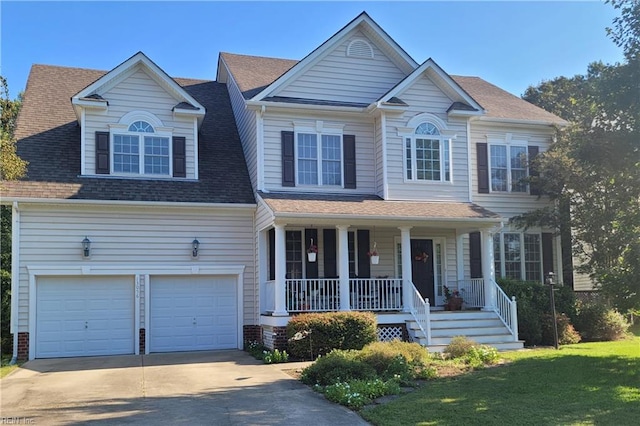 view of front of house featuring covered porch, a garage, and a front lawn