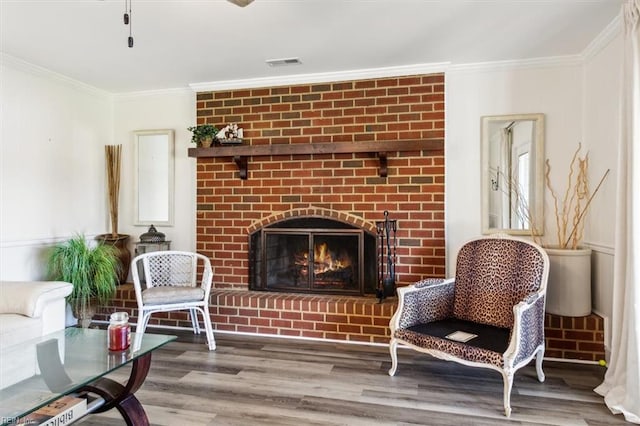 living area with ornamental molding, a fireplace, and hardwood / wood-style floors