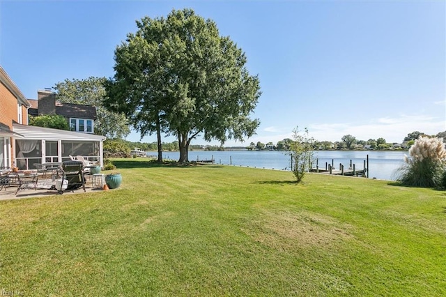 view of yard with a water view, a sunroom, and a dock