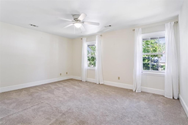 empty room with ceiling fan, light colored carpet, and a healthy amount of sunlight