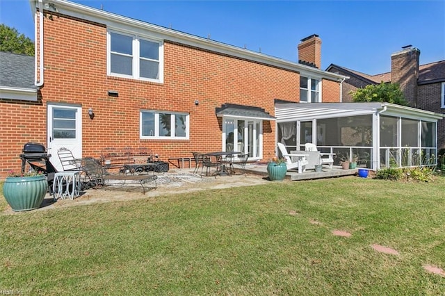 rear view of property with a yard, a sunroom, and a patio