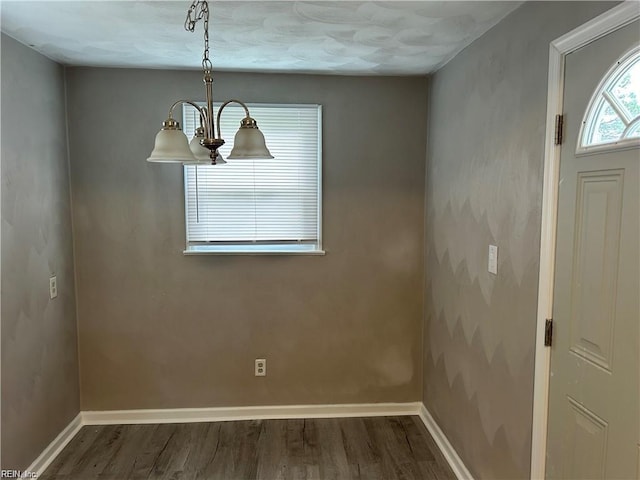 unfurnished dining area with a notable chandelier and dark hardwood / wood-style floors