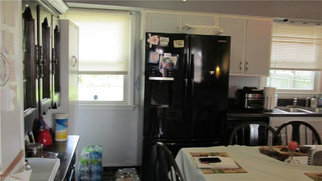 kitchen with a wealth of natural light, black appliances, white cabinets, and sink