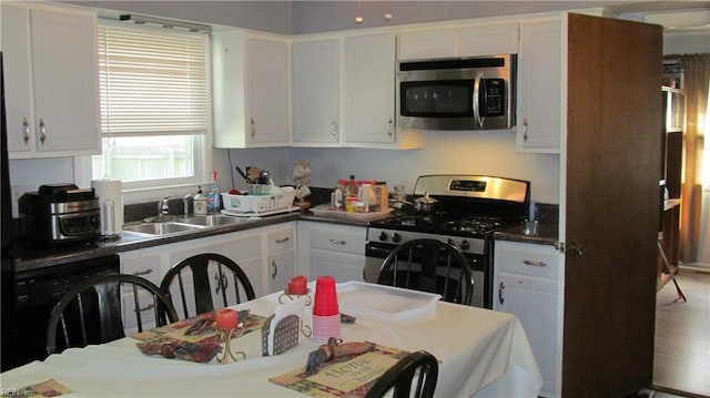 kitchen featuring hardwood / wood-style flooring, appliances with stainless steel finishes, sink, and white cabinetry