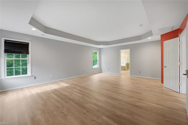 unfurnished room with a raised ceiling and light hardwood / wood-style flooring