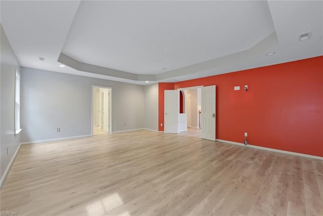 unfurnished room featuring a tray ceiling and light hardwood / wood-style floors