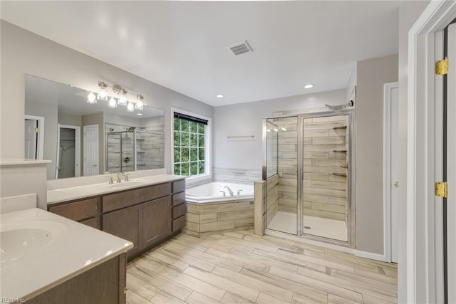 bathroom with shower with separate bathtub, hardwood / wood-style flooring, and vanity