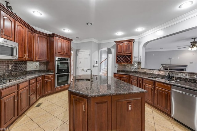 kitchen with ornamental molding, a center island with sink, appliances with stainless steel finishes, and sink