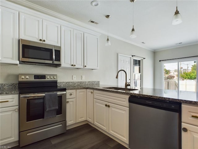 kitchen featuring appliances with stainless steel finishes, white cabinets, crown molding, decorative light fixtures, and sink