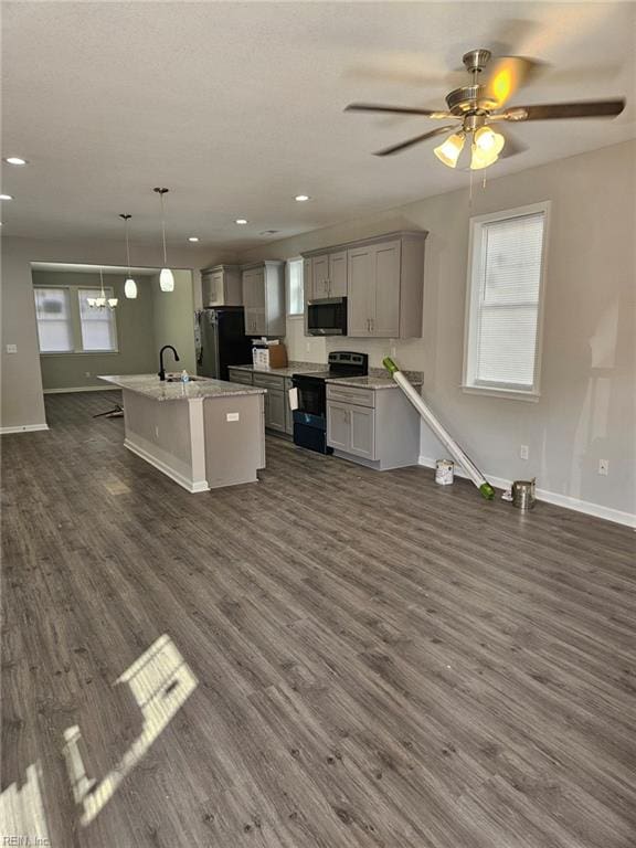 kitchen featuring dark hardwood / wood-style floors, a kitchen island with sink, hanging light fixtures, gray cabinetry, and black appliances