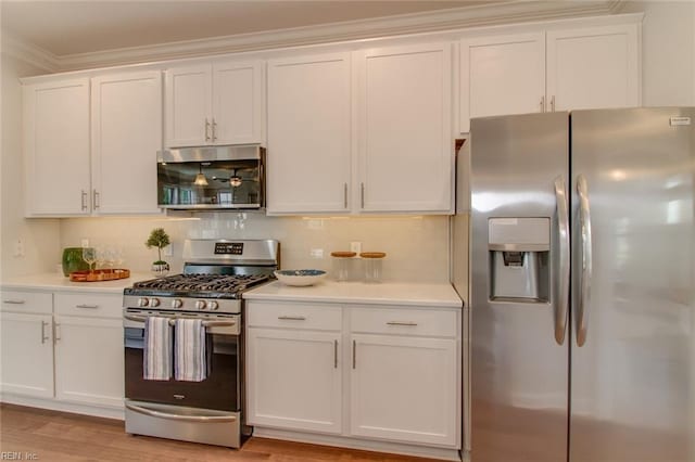 kitchen featuring light hardwood / wood-style flooring, white cabinets, appliances with stainless steel finishes, and ornamental molding