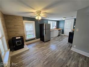 interior space with ceiling fan, stainless steel fridge, hardwood / wood-style floors, and a wood stove