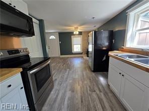 kitchen featuring light wood-type flooring, black appliances, ceiling fan, and white cabinetry