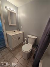 bathroom featuring walk in shower, vanity, toilet, and tile patterned floors