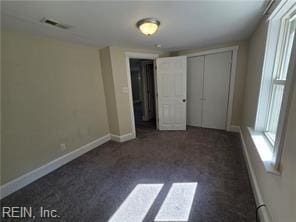 unfurnished bedroom featuring a closet and dark colored carpet