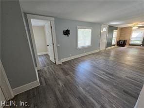 unfurnished living room featuring plenty of natural light and dark hardwood / wood-style flooring