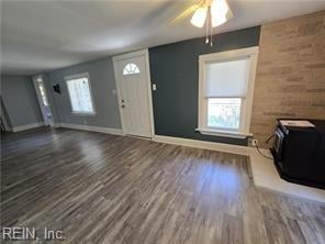 entrance foyer with wooden walls, ceiling fan, and dark wood-type flooring