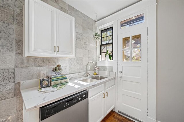 kitchen with light stone counters, dishwasher, hardwood / wood-style floors, white cabinets, and sink