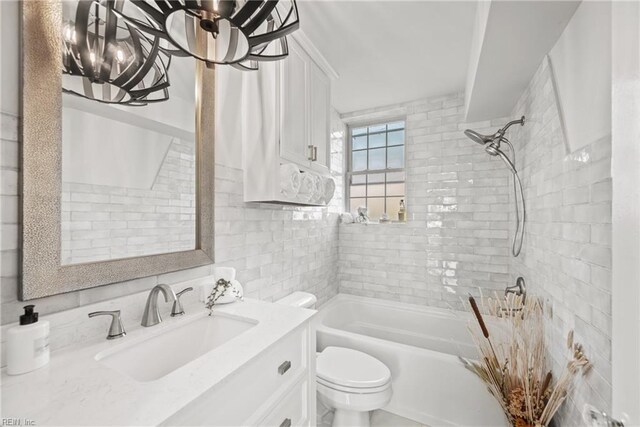 full bathroom with decorative backsplash, tiled shower / bath, toilet, and vanity