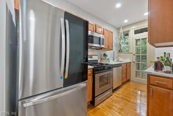 kitchen with decorative backsplash, appliances with stainless steel finishes, light hardwood / wood-style floors, and sink