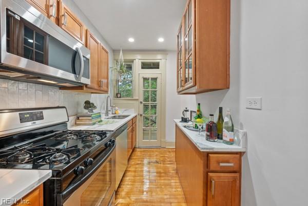 kitchen with tasteful backsplash, appliances with stainless steel finishes, sink, and light hardwood / wood-style floors