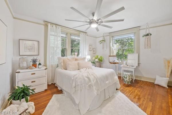 bedroom with ornamental molding, wood-type flooring, and ceiling fan