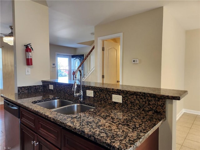 kitchen with light tile patterned floors, sink, kitchen peninsula, dishwasher, and dark stone counters