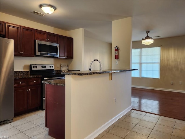 kitchen featuring light wood-type flooring, dark stone counters, a kitchen breakfast bar, sink, and stainless steel appliances