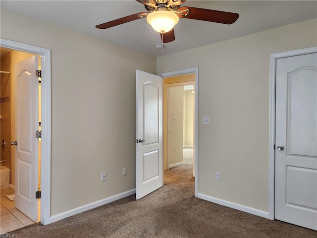 unfurnished bedroom featuring ceiling fan, light colored carpet, and ensuite bath