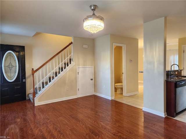 foyer entrance with light wood-type flooring, sink, and an inviting chandelier