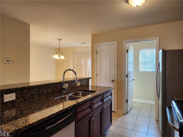 kitchen featuring dark brown cabinetry, stainless steel appliances, sink, dark stone counters, and decorative light fixtures