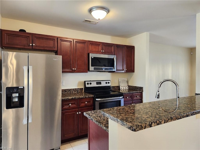 kitchen with stainless steel appliances, dark stone countertops, sink, kitchen peninsula, and light tile patterned floors