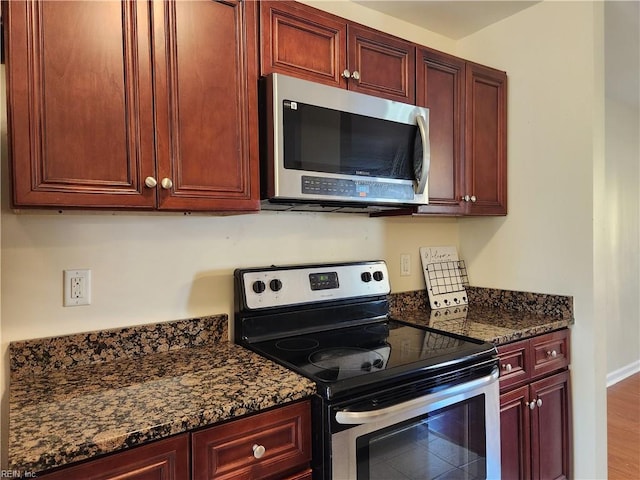 kitchen featuring stainless steel appliances, dark stone countertops, and hardwood / wood-style floors