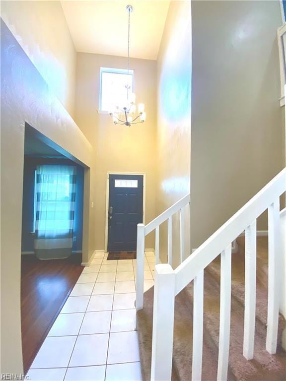 foyer entrance with a high ceiling, light wood-type flooring, and a notable chandelier