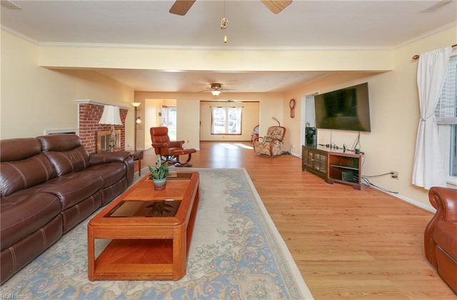 living room with a brick fireplace, light hardwood / wood-style flooring, and crown molding