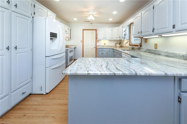 kitchen with kitchen peninsula, ceiling fan, white appliances, and light hardwood / wood-style floors