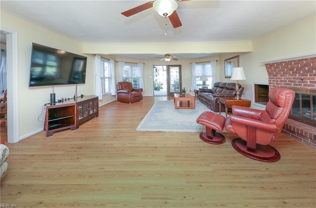 living room with light wood-type flooring, a fireplace, and ceiling fan