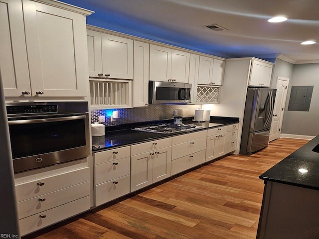 kitchen with light hardwood / wood-style floors, crown molding, stainless steel appliances, backsplash, and white cabinetry