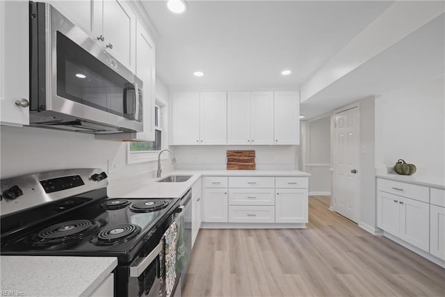 kitchen featuring appliances with stainless steel finishes, sink, white cabinetry, and light hardwood / wood-style flooring