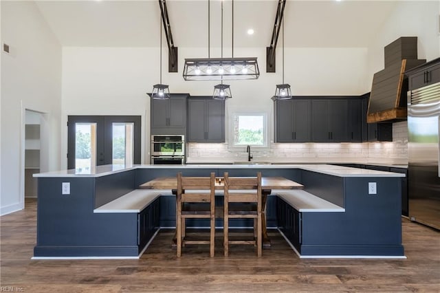 kitchen featuring high vaulted ceiling, dark wood-type flooring, a center island, and stainless steel appliances