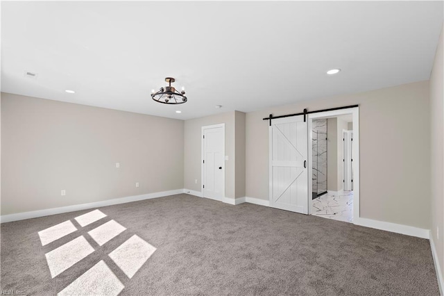 unfurnished bedroom featuring light carpet and a barn door